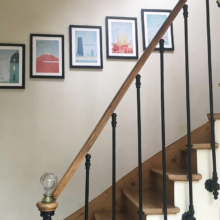 Vintage travel posters hung on staircase. Artwork by Travel Poster Co. / Henry Rivers. Framed vintage Travel art collection.